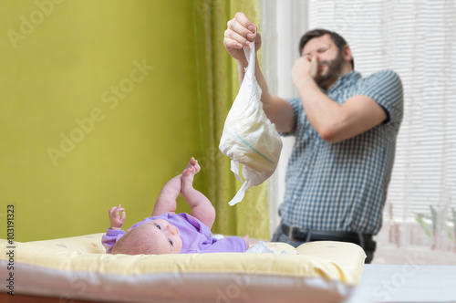 Baby care concept. Father od dad is changing stinky diaper.