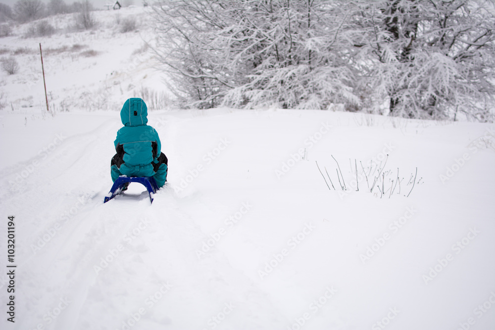 Kid with a sledge, photographed from behind. Winter landscape on mountain Kid with a sledge, photographed from behind. Winter landscape on mountain