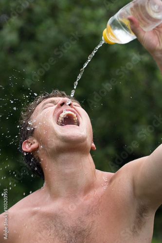 The boy is drinking water in the hot summer