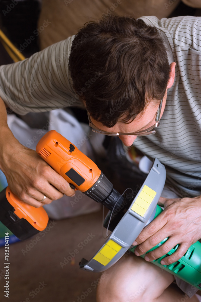 A man with a screwdriver and trimmer for grass