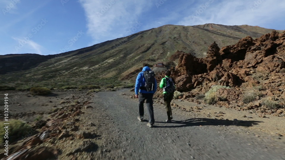 Hiking couple walking on hike on volcano Teide, Tenerife. Hikers trekking on trail path living active hiker outdoor lifestyle on Canary Islands, Spain Hiking couple walking on hike on volcano Teide, Tenerife. Hikers trekking on trail path living active hiker outdoor lifestyle on Canary Islands, Spain