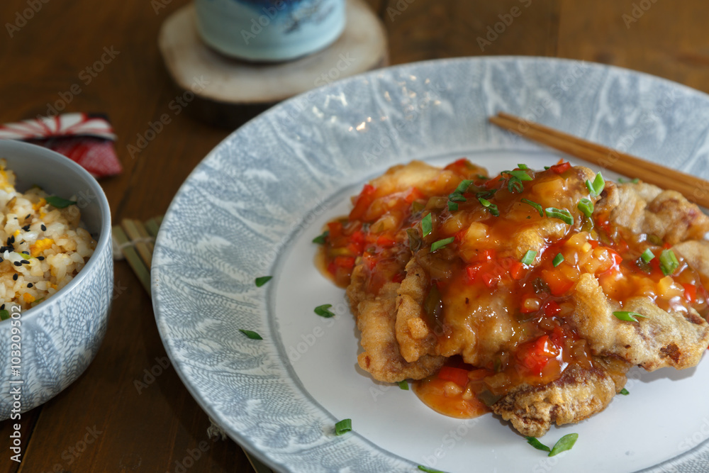 Sweet and sour pork and rice on plate with chopsticks, Chenese cuisine