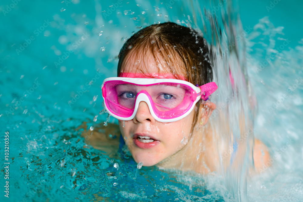 Naklejka premium Cute happy girl in pink goggles mask in the swimming pool
