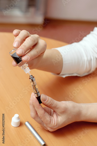 Female hands fill with liquid in the clearomizers electronic cig photo