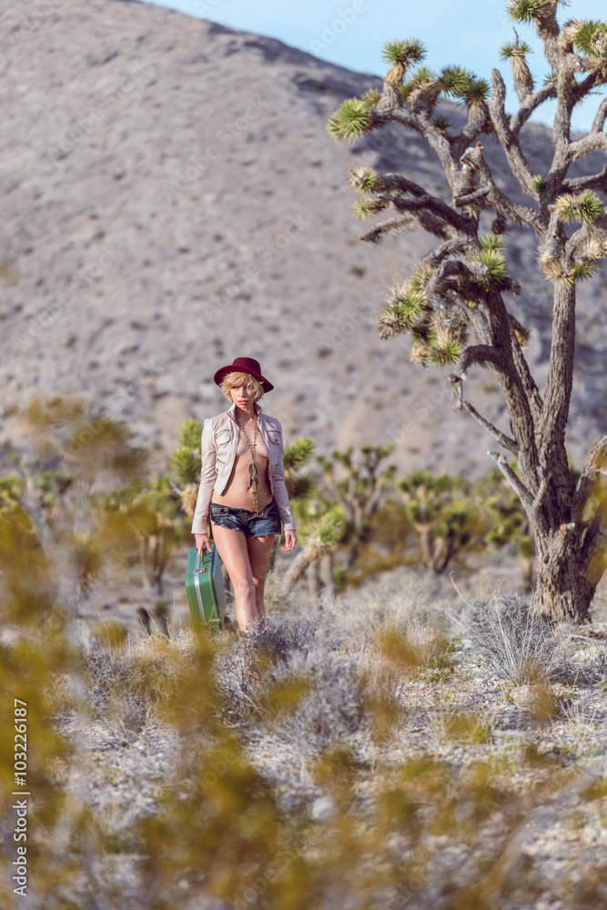 woman traveler walking with suitcase in desert woman traveler walking with suitcase in desert