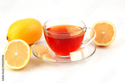 Glass cup of tea surrounded by lemons.