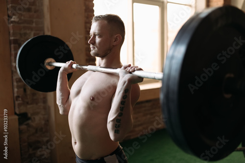 Strong man lifting barbell at the gym