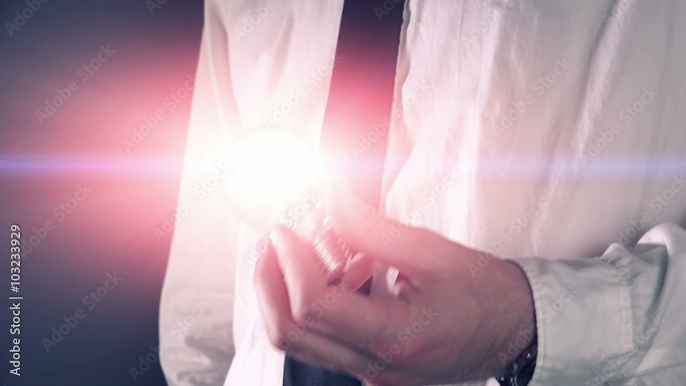 Business idea and vision, businessman holding shining light bulb, concept of new ideas, innovation, invention and creativity.