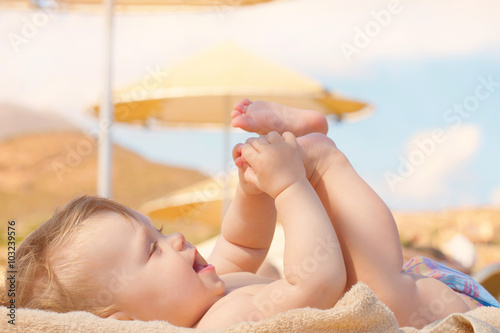 Happy baby sunbathing on the beach sunbed.