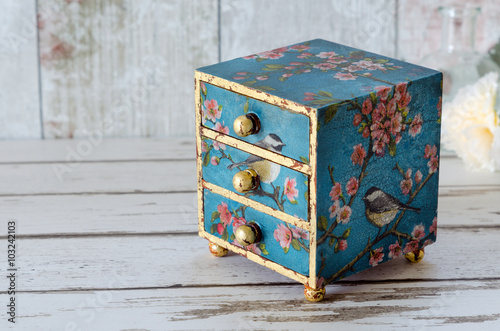 A handmade mini chest of three drawers decoupaged with blue floral vintage paper and gold leaf photo