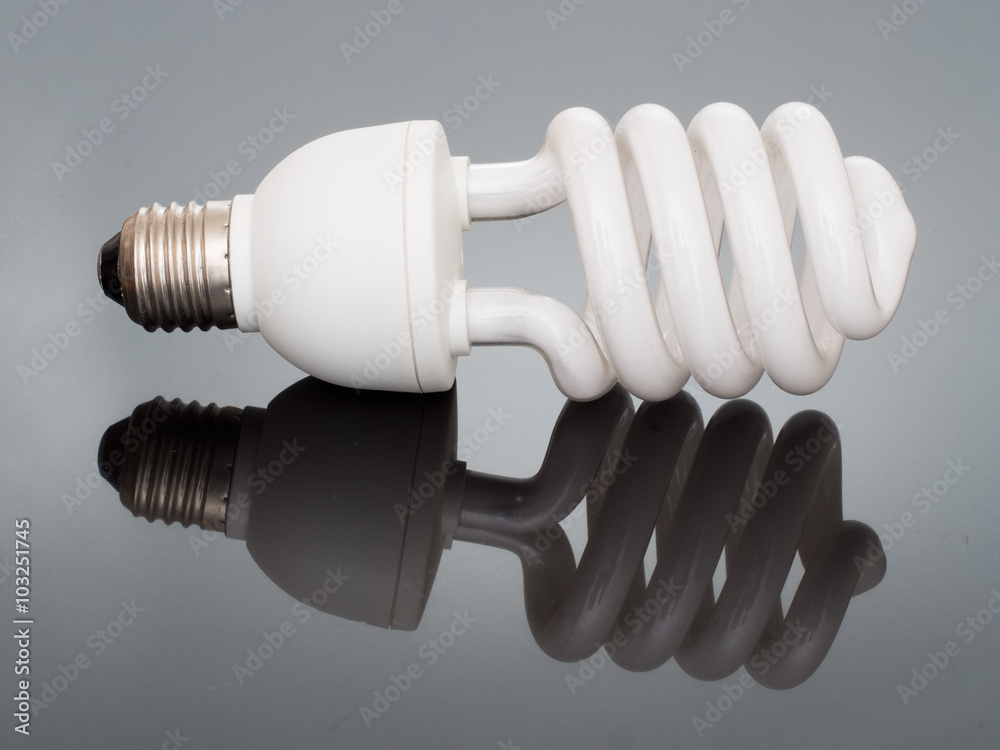 Modern energy saving light bulb. Mirrored on shiny textured surface. Modern energy saving light bulb. Mirrored on shiny textured surface.