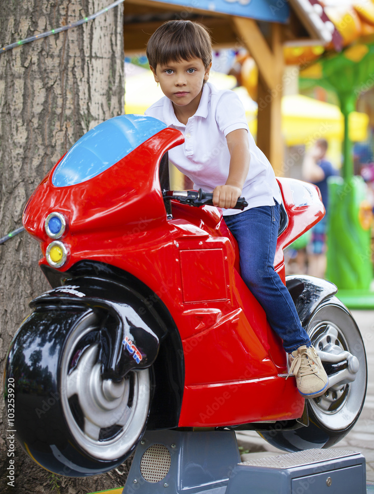 Little boy sitting on a toy motorcycle in an amusement park Little boy sitting on a toy motorcycle in an amusement park
