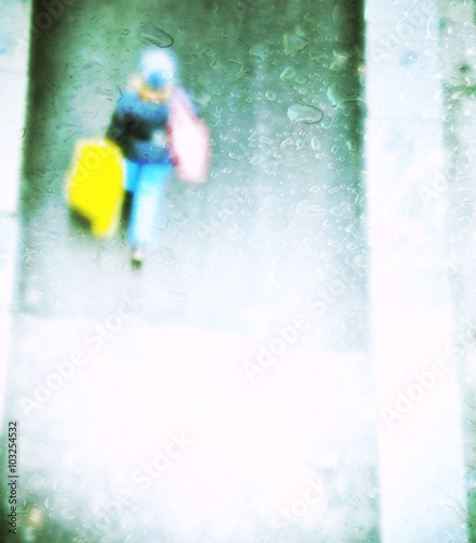 blurred people in the street walking shopping behind wet glass © imagosrb