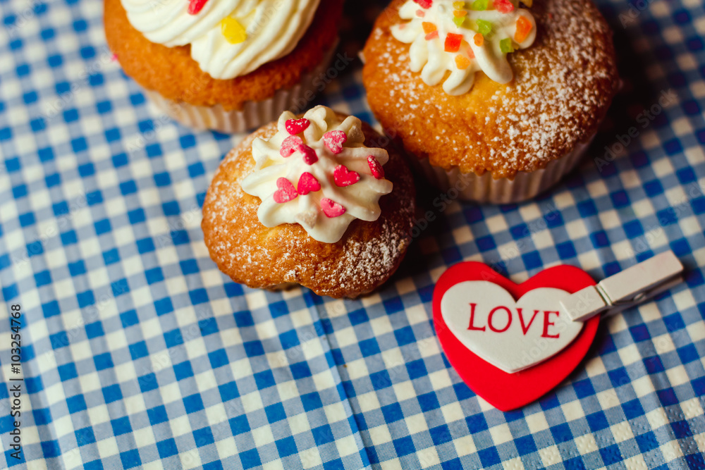 Beautiful cupcakes and a heart with the inscription Love lie on a vintage checkered tablecloth Beautiful cupcakes and a heart with the inscription Love lie on a vintage checkered tablecloth
