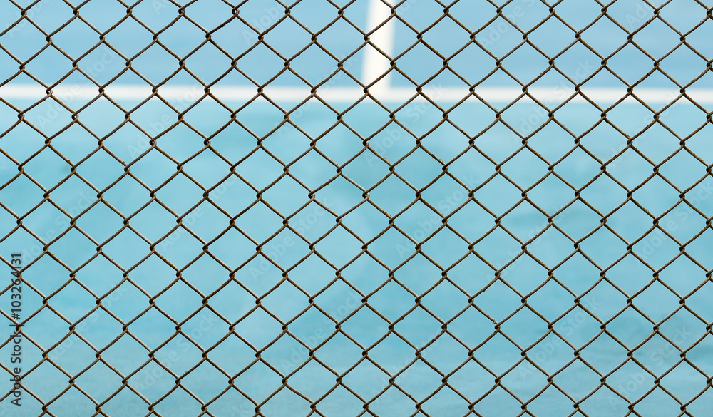 Metal Mesh fence on blurred background of blue tennis hard court Metal Mesh fence on blurred background of blue tennis hard court