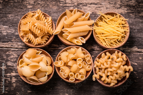 Various mix of pasta on wooden rustic background. Diet and food