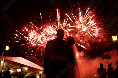 Happy hugging bride and groom watching beautiful colorful firewo photo