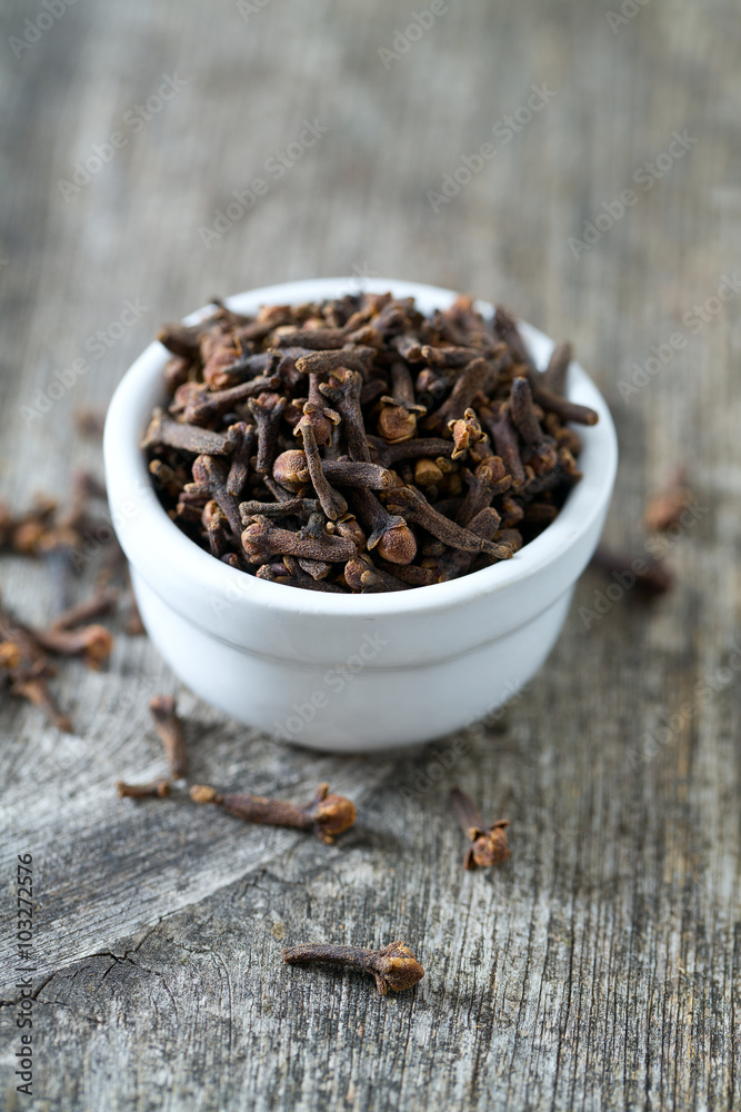 cloves in a bowl on wooden surface cloves in a bowl on wooden surface
