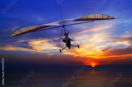 The motorized hang glider in the sunset above sea