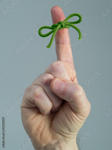 Photograph of a man's hand in close up with a green string tied around the index finger as a St. Patrick's Day reminder. photo