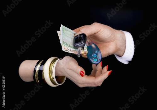 Men's hand giving to  woman's hand eurobanknotes and car keys photo