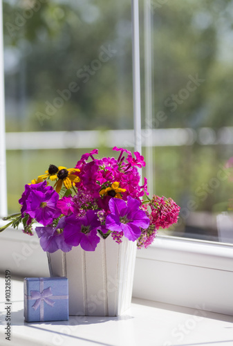 Spring pink flower composition and blue gift box near the window
