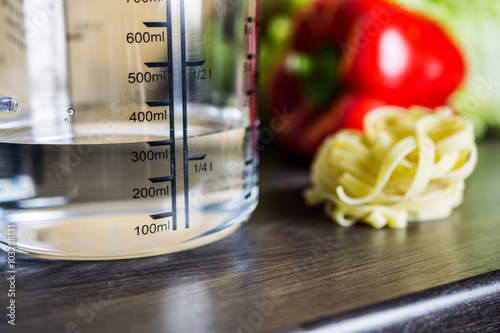 300ccm / 300ml Of Water In A Measuring Cup On A Kitchen Counter With Food photo