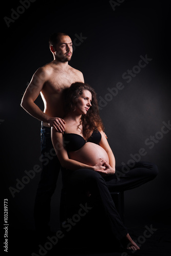 handsome young man embracing his beautiful pregnant wife