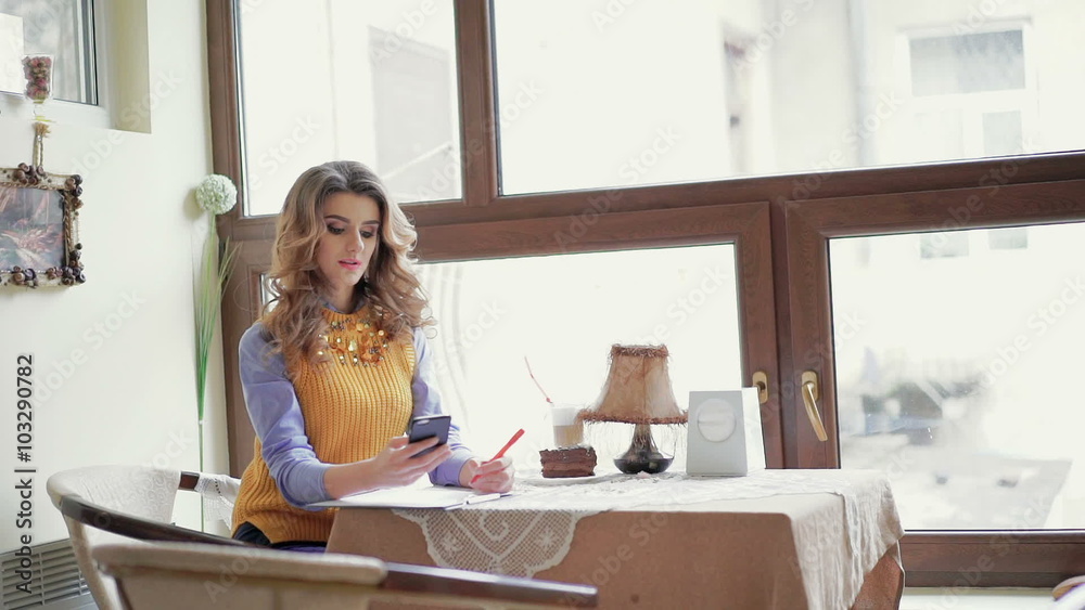 Chic business lady writing, using phone at the table in cafe Chic business lady writing, using phone at the table in cafe