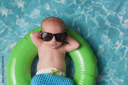 Newborn Baby Boy Floating on an Inflatable Swim Ring photo