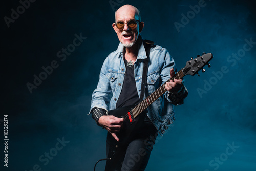 Bald heavy metal senior man with electric flying-v guitar in fro
