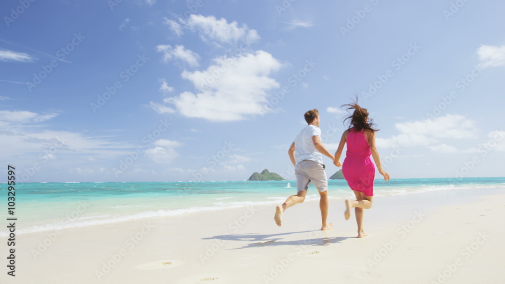 Beach couple happy running having fun on Hawaii. Romantic couple cheerful and full of happiness on travel vacation on Lanikai beach, Oahu, Hawaii, USA with Mokulua Islands. Asian woman, Caucasian man Beach couple happy running having fun on Hawaii. Romantic couple cheerful and full of happiness on travel vacation on Lanikai beach, Oahu, Hawaii, USA with Mokulua Islands. Asian woman, Caucasian man
