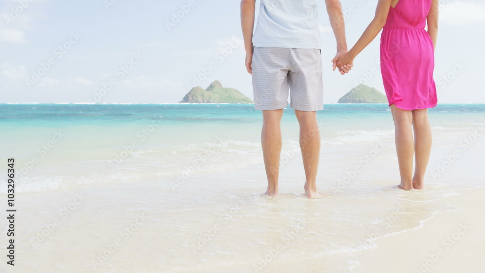 Holding hands romantic newlyweds couple on beach. Closeup of male and female hands with a sunny honeymoon during travel summer holidays on Lanikai beach on Oahu, Hawaii, USA with Na Mokulua Islands Holding hands romantic newlyweds couple on beach. Closeup of male and female hands with a sunny honeymoon during travel summer holidays on Lanikai beach on Oahu, Hawaii, USA with Na Mokulua Islands