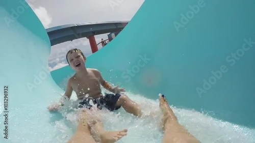Happy young boy going down curved waterslide in slow motion Cape Town