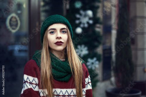 Street portrait of young beautiful woman with long blond hair wearing stylish winter clothes. Model looking at camera. Female fashion concept. Toned photo