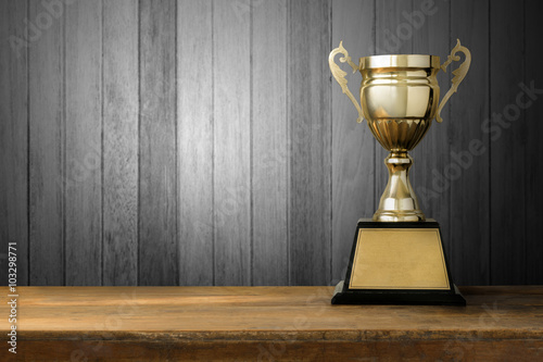 champion golden trophy on wood table with blackboard copy space