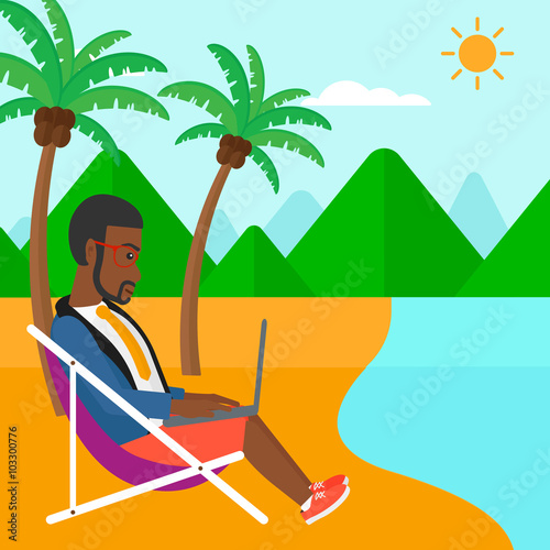 Businessman sitting in chaise lounge with laptop.