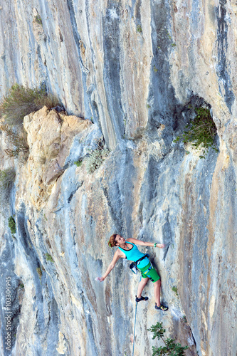 Young Female Climber assaulting vertical Rocky Wall