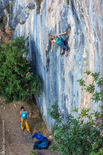 Two Climbers work in pair on vertical rocky Wall