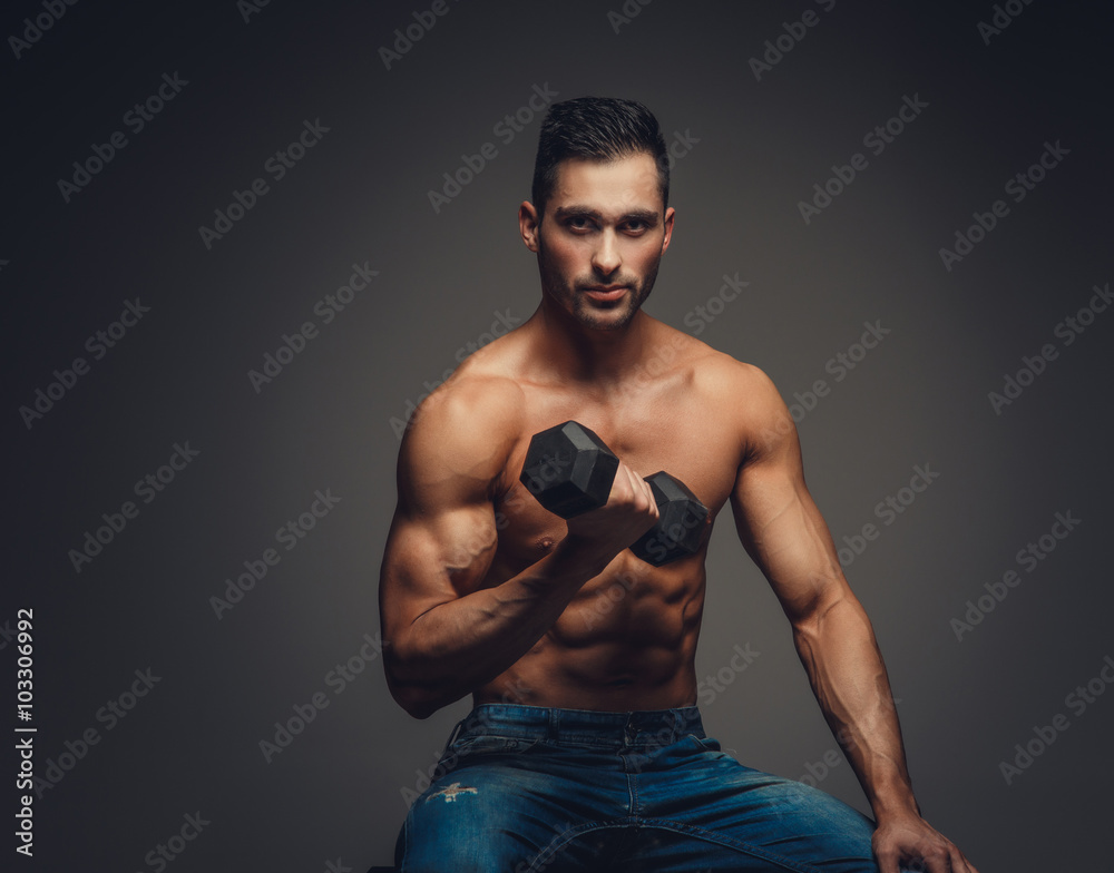 Man in a jeans holding a dumbbell.