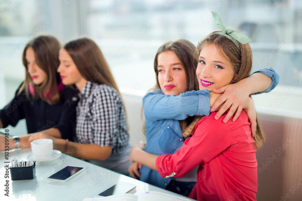 Portrait of four young women sitting at the table in the cafe