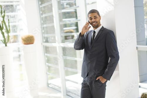 Handsome young black man with mobile phone in the office