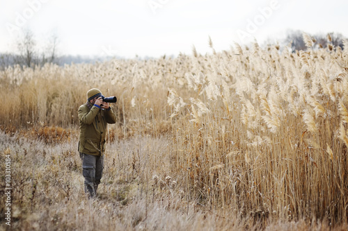 a man with a camera on a background of yellow high grass. Photog © Evgeniy Kalinovskiy