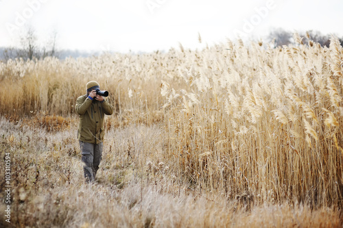 a man with a camera on a background of yellow high grass. Photog © Evgeniy Kalinovskiy