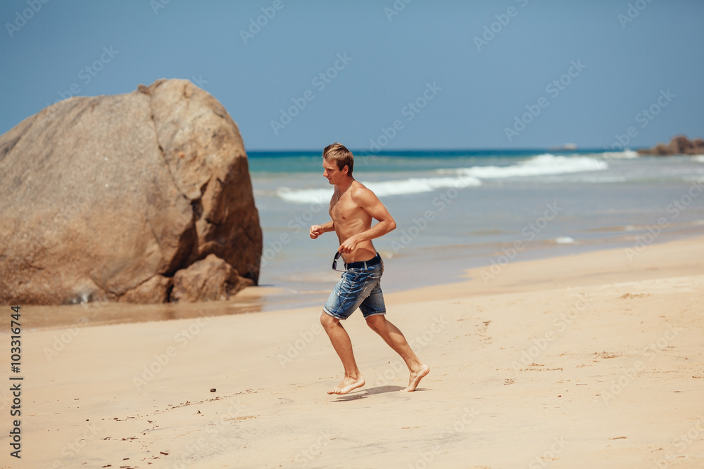 Man running on the beach with the sea in the background. Male ru