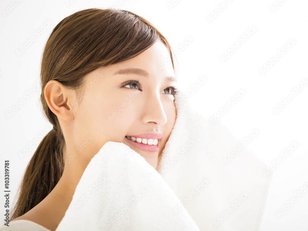 young woman cleaning her face with  towel