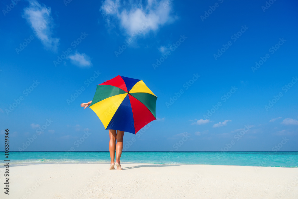 Girl with an colorful  umbrella on the sandy beach