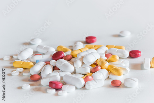 several different colored and sized medicine drug pills on white