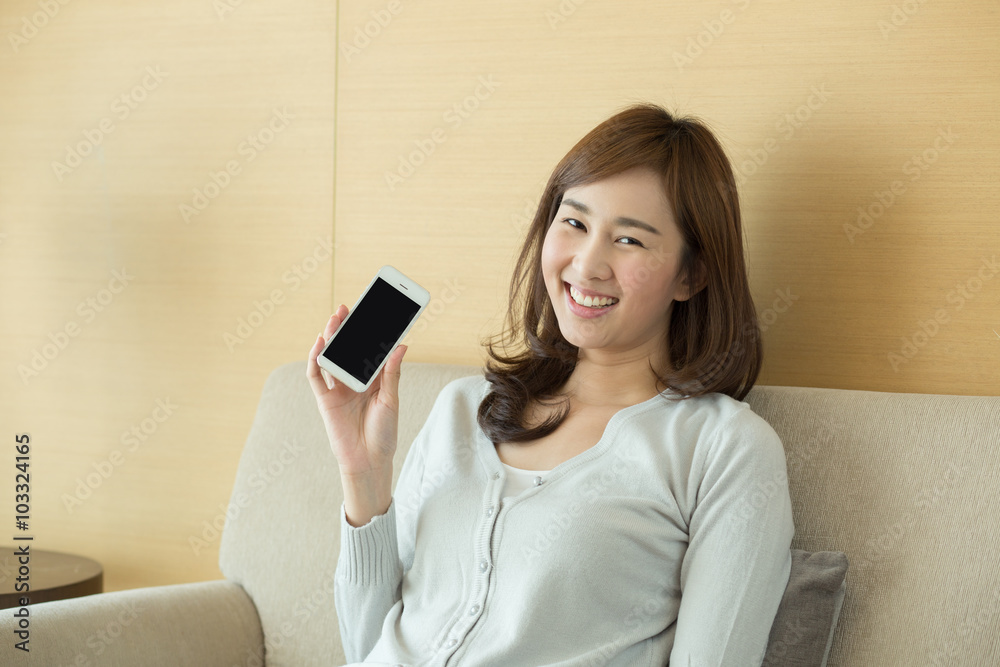 Young woman showing her smartphone while relaxing at home Young woman showing her smartphone while relaxing at home
