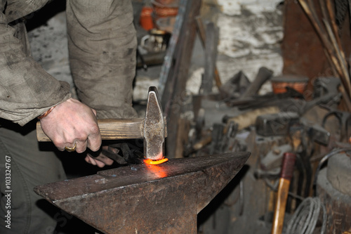 Blacksmith forges a red-hot metal hammer